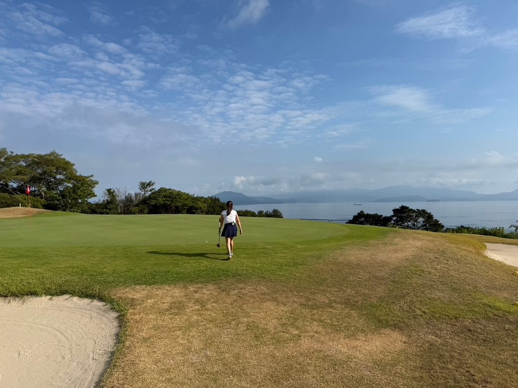 Golfer walking toward the green on an ocean-view hole